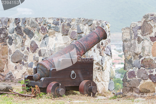 Image of Very old rusted canon on top of an old wall