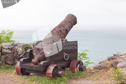 Image of Very old rusted canon pointing at a bay