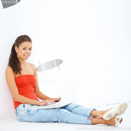 Image of Young smiling girl sitting on the floor with laptop