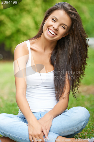 Image of Happy young brunette relaxing in park