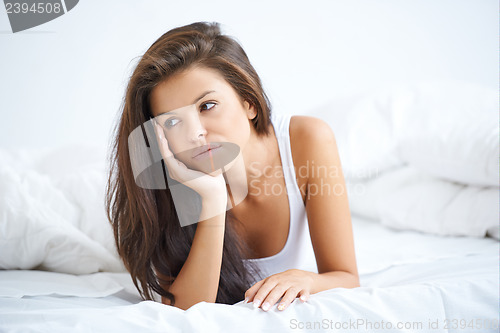 Image of Brunette woman lying on bed in bad mood