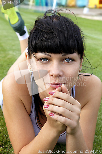 Image of sportswoman lies on green grass