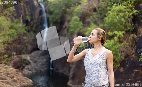 Image of Young healthy woman drinks water from bottle.Outdoor