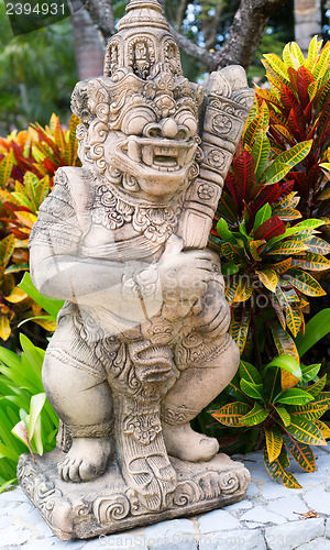 Image of Thai stone god in the bushes of tropical plants