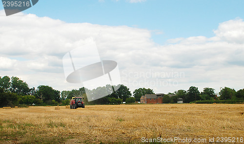 Image of Red tractor baling straw in a farm field 