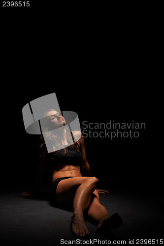 Image of Young muscular woman under bright light