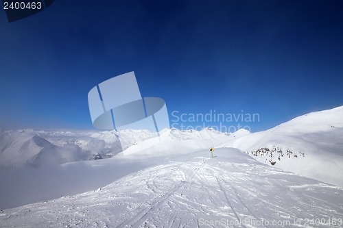Image of Warning sing on ski slope and snowy mountains in haze