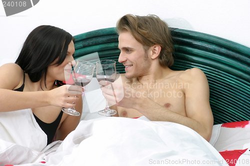 Image of Couple in bed drinking wine