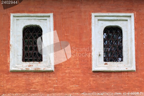 Image of Two windows with bars on the red wall