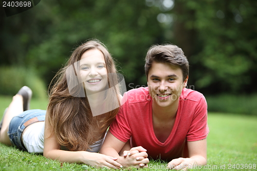 Image of Attractive young couple lying on the grass
