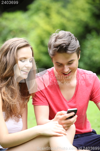 Image of Young teenage couple laughing at an sms