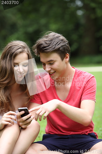 Image of Teenage couple reading a text message