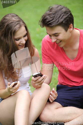 Image of Couple of teenagers looking at their mobile phones