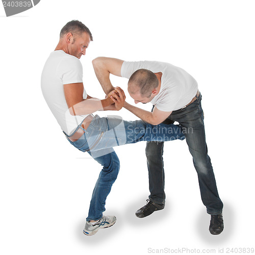 Image of Man trying to kidnap another man, selfdefense, kicking in groin