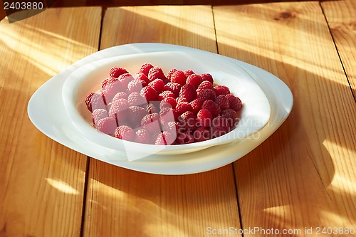 Image of Raspberries in plate on the wooden table