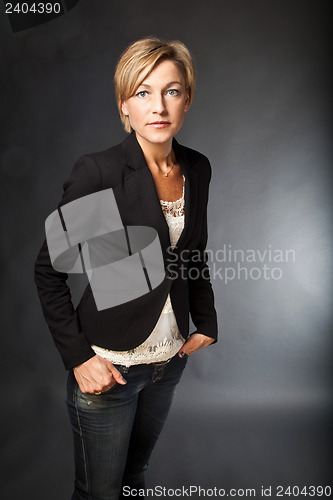 Image of Woman standing shot in studio, hands in her pockets