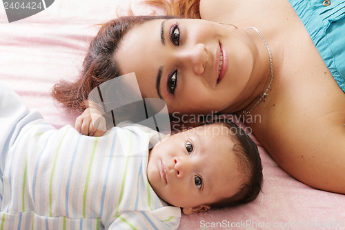 Image of Portrait of happy young attractive hispanic mother lying with he