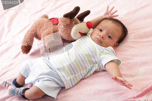 Image of hispanic baby with teddy bear laying on bed
