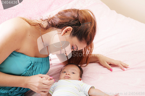 Image of attractive mother lying with her baby on the bed at home 