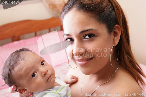 Image of beautiful hispanic young mother is holding her newborn baby