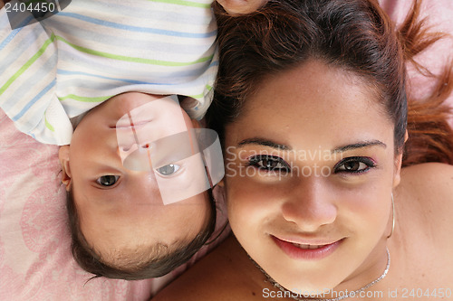 Image of Portrait of a beautiful hispanic happy mother with baby lying do