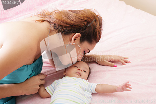 Image of Young mother kissing her small newborn 