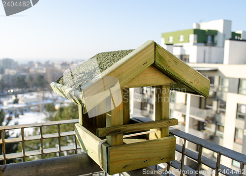 Image of wooden small bird feeder on the balcony edge  