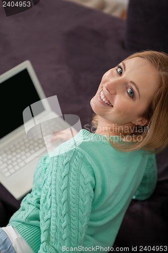 Image of smiling woman on couch with notebook