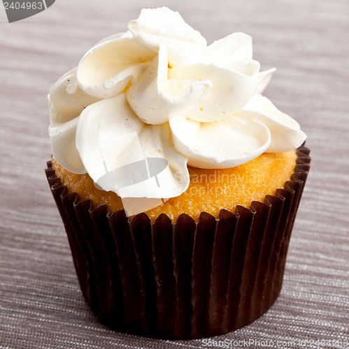 Image of tasty sweet homemade cupcakes with cream on table