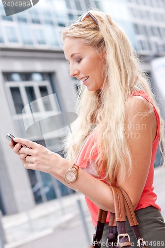 Image of attractive young blonde woman talking on the phone outdoor