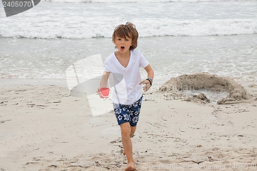 Image of cute little boy playing in sand on beach in summer