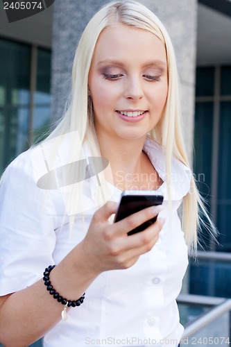 Image of smiling attractive blonde businesswoman with smartphone 