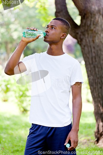 Image of athletic african young man drinking water outdoor
