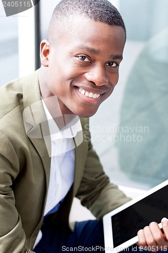 Image of smiling successful businessman with tablet pc outdoor