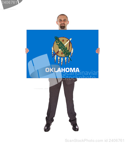 Image of Smiling businessman holding a big card, flag of Oklahoma