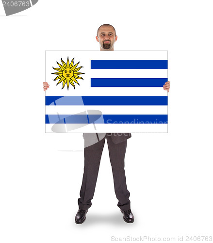 Image of Smiling businessman holding a big card, flag of Uruguay