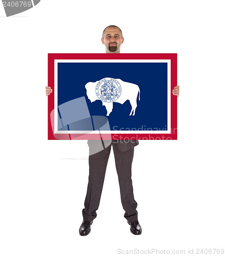 Image of Smiling businessman holding a big card, flag of Wyoming