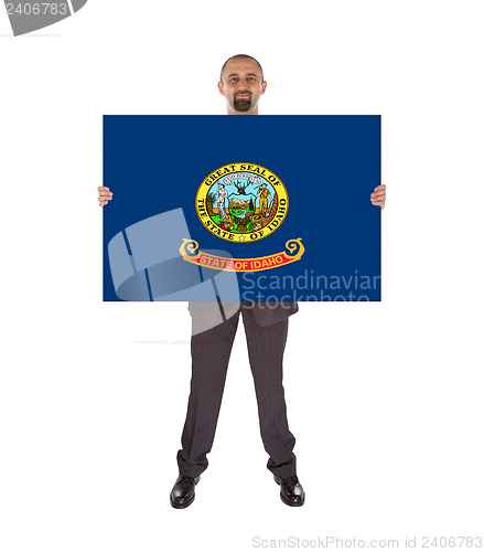 Image of Smiling businessman holding a big card, flag of Idaho