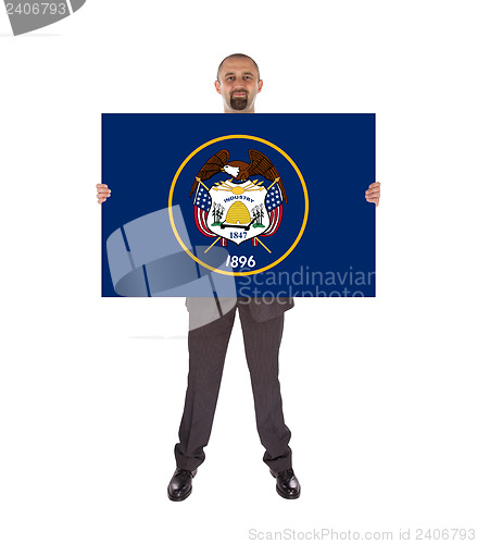 Image of Smiling businessman holding a big card, flag of Utah