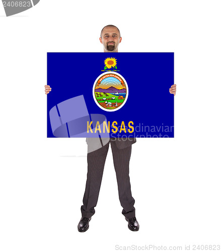 Image of Smiling businessman holding a big card, flag of Kansas