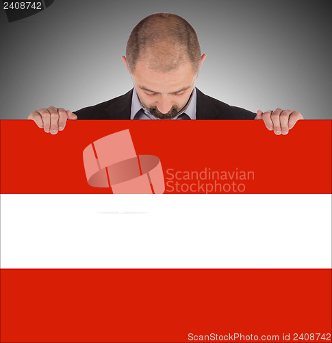Image of Smiling businessman holding a big card, flag of Austria