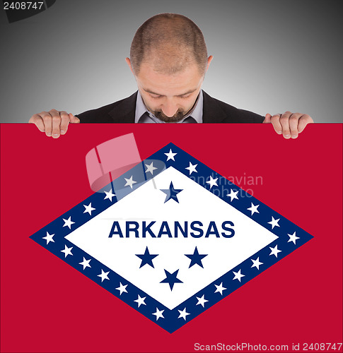 Image of Smiling businessman holding a big card, flag of Arkansas