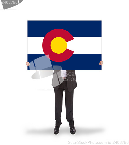 Image of Smiling businessman holding a big card, flag of Colorado