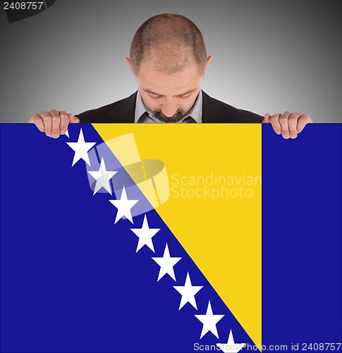 Image of Smiling businessman holding a big card, flag of Bosnia and Herze