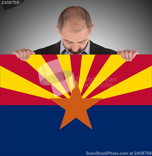 Image of Smiling businessman holding a big card, flag of Arizona