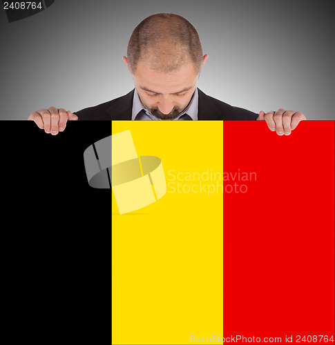 Image of Smiling businessman holding a big card, flag of Belgium