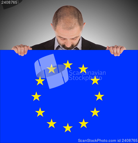Image of Smiling businessman holding a big card, flag of the European Uni