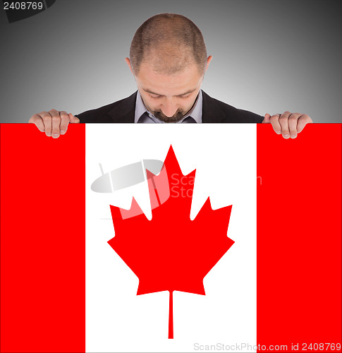 Image of Smiling businessman holding a big card, flag of Canada