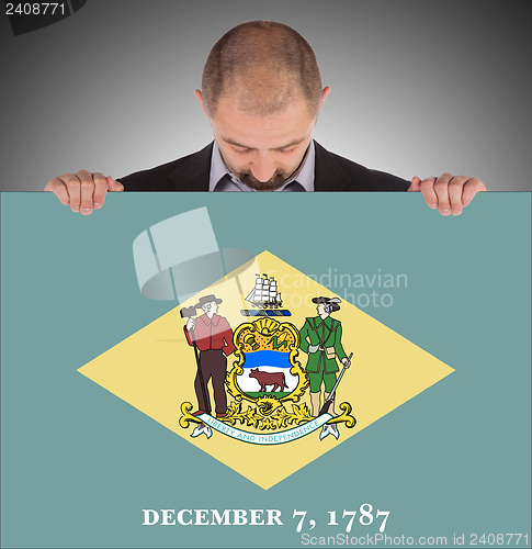 Image of Smiling businessman holding a big card, flag of Delaware