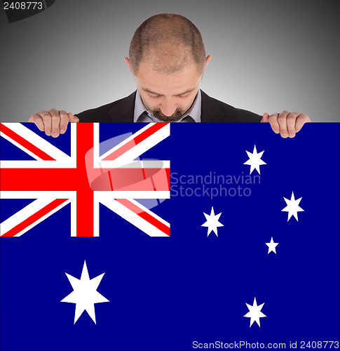Image of Smiling businessman holding a big card, flag of Australia